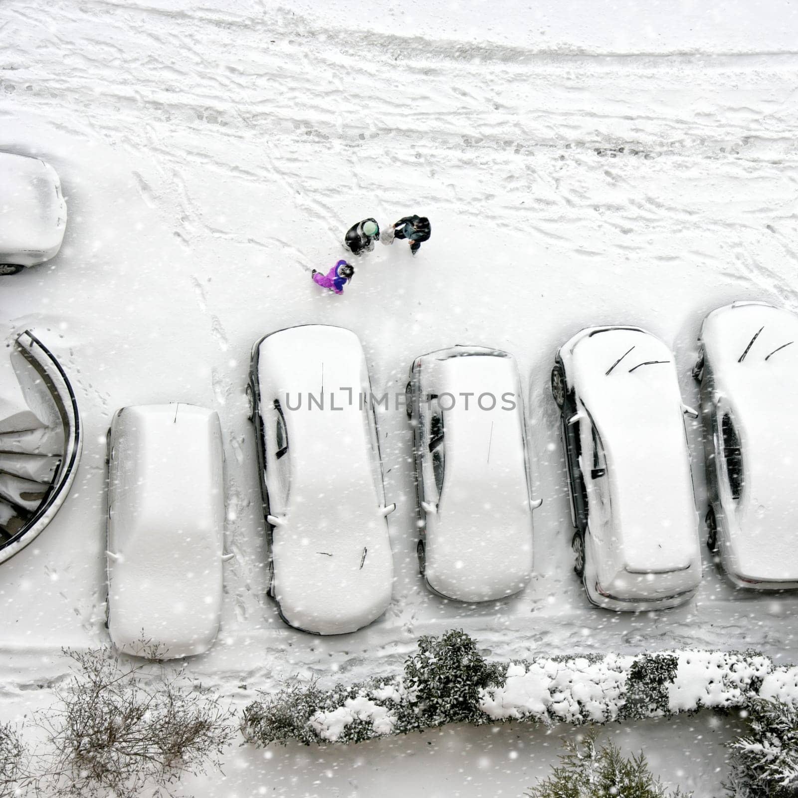 Elevated view of children play in snow covered parking lot