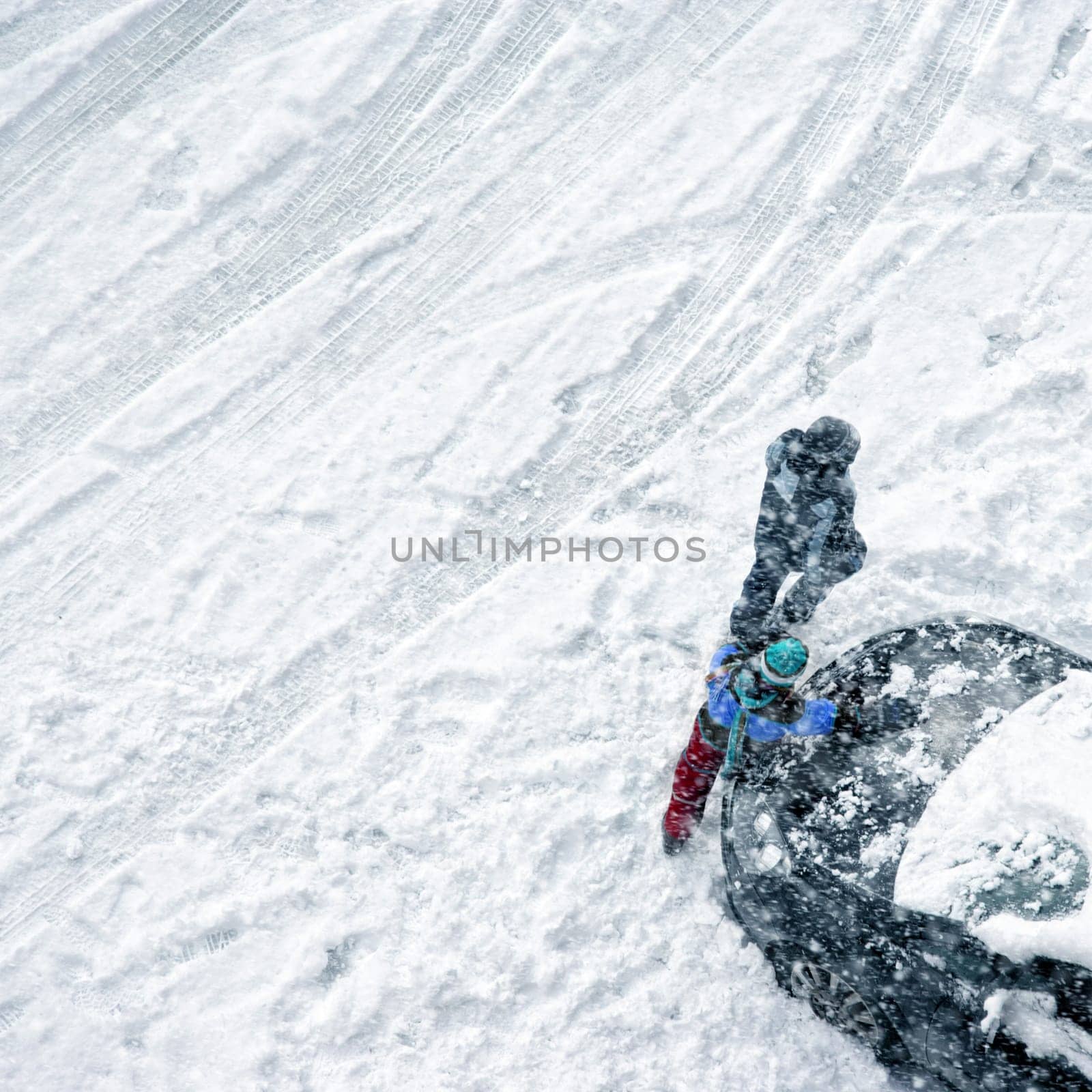 Elevated view of children play in snow covered parking lot