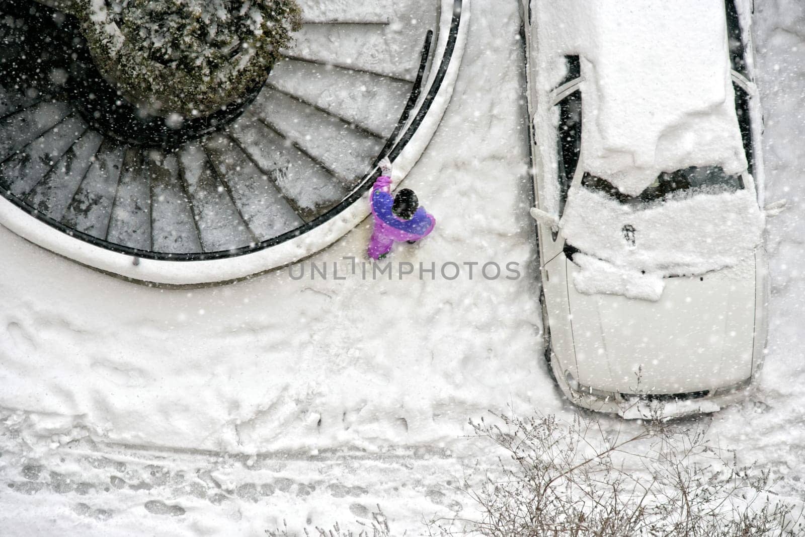 Elevated view of child play in snow covered parking lot