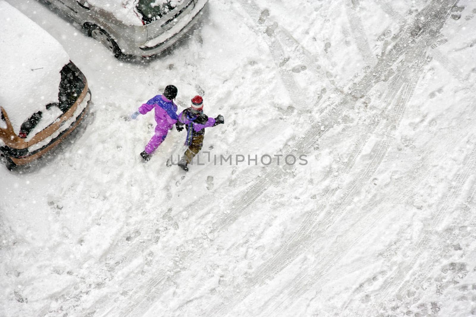 Elevated view of children play in snow covered parking lot