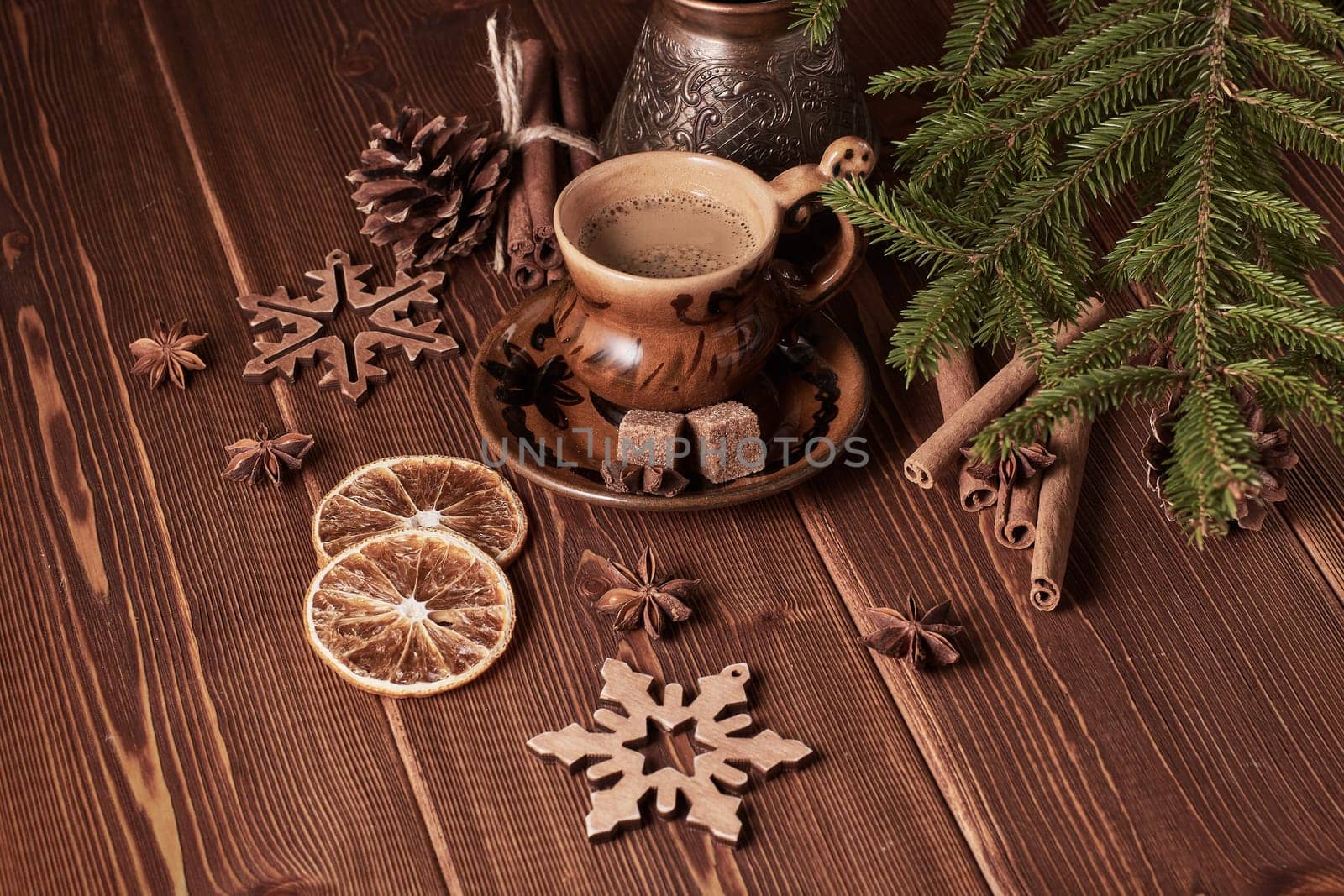 Cup of coffee, fir tree branches with decorations on a wooden brown background. Christmas and New Year treat.