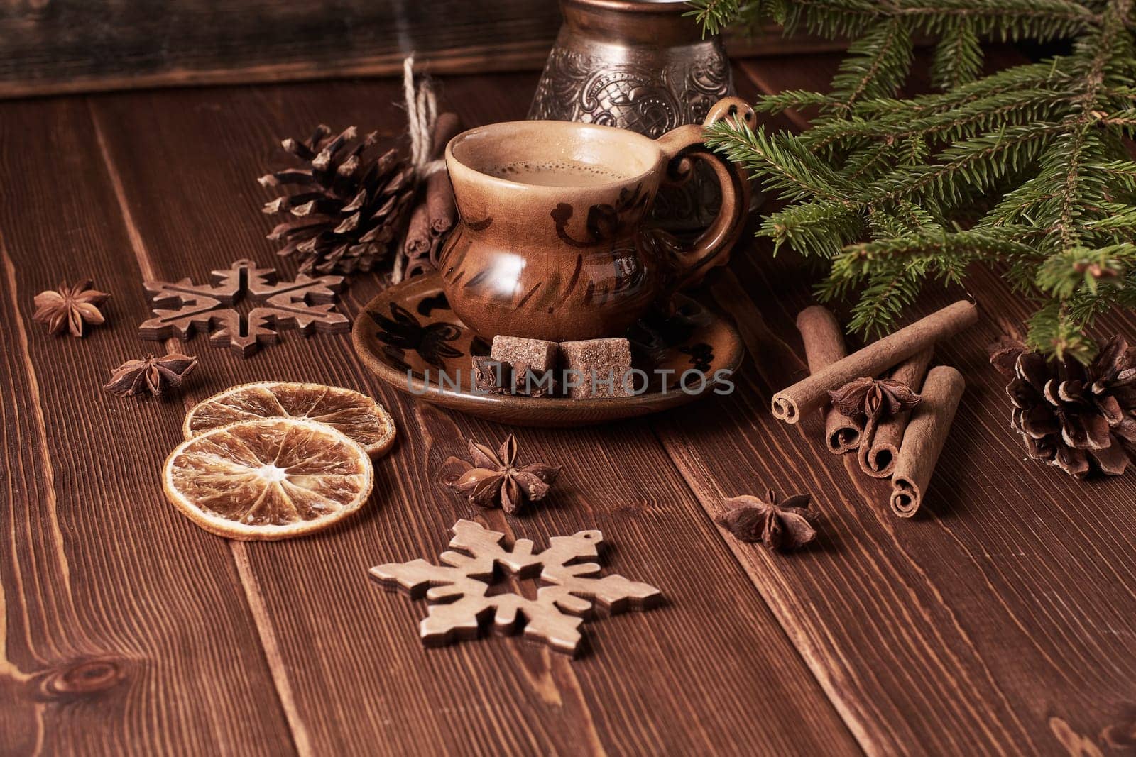 Cup of coffee, fir tree branches with decorations on a wooden brown background. Christmas and New Year treat.