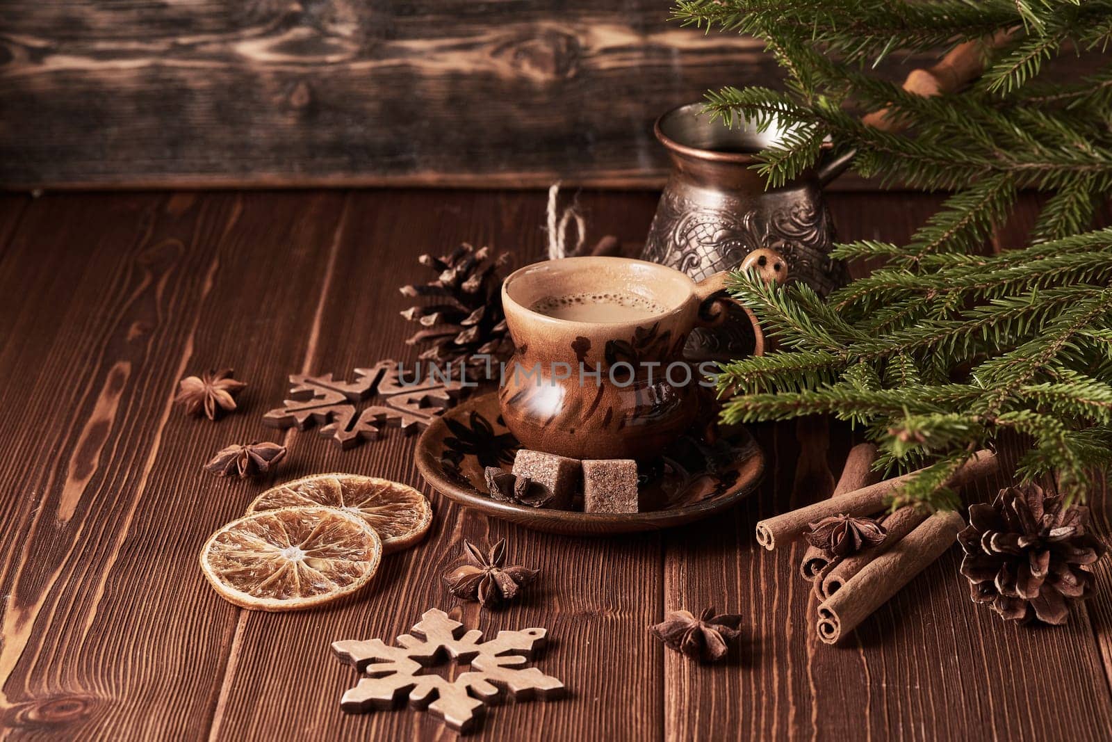 Cup of coffee, fir tree branches with decorations on a wooden brown background. Christmas and New Year treat.