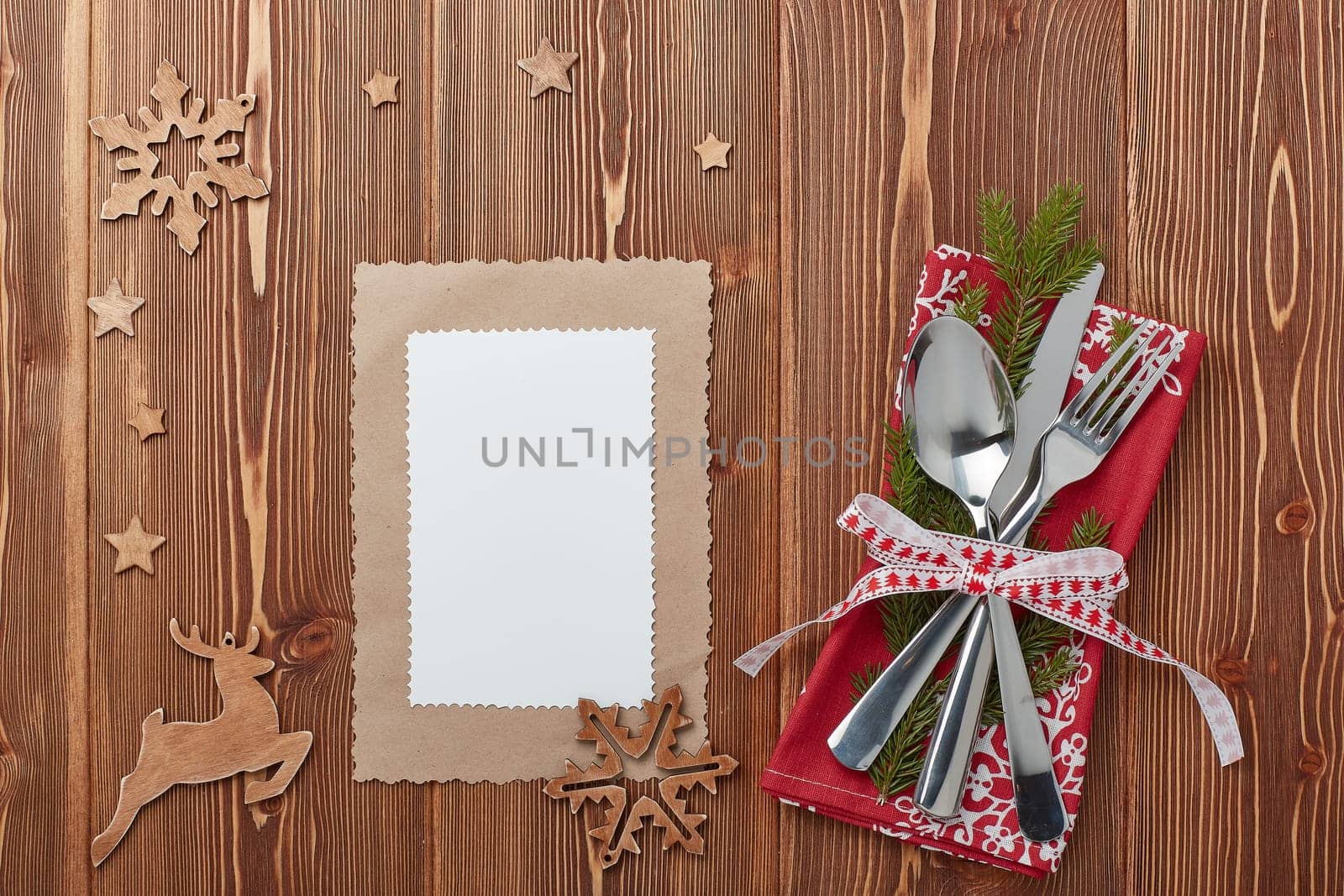 Spoon, knife and fork on red napkin with fir tree branch on a wooden background. Top view with copy space for adding your content. Menu. Advertising