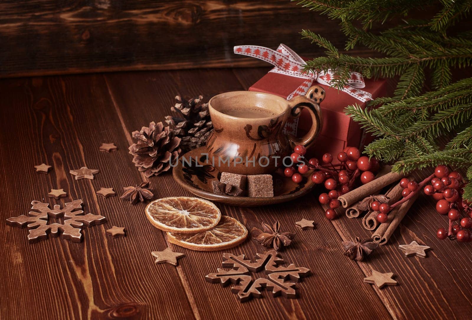 Cup of coffee, gift box, fir tree branches with decorations on a wooden brown background. Christmas and New Year.