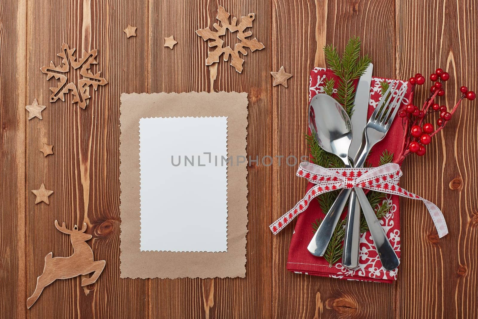 Spoon, knife and fork on red napkin with fir tree branch on a wooden background. Top view with copy space for adding your content. Menu. Advertising