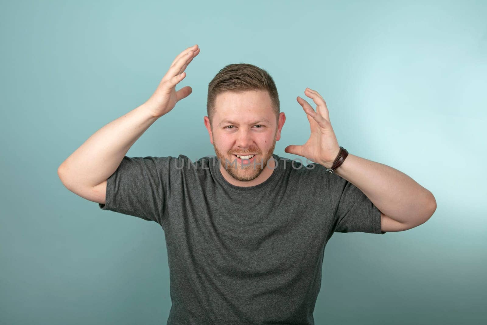 Frustrated angry man snarling and gesturing with his hands either side of his head over a grey background