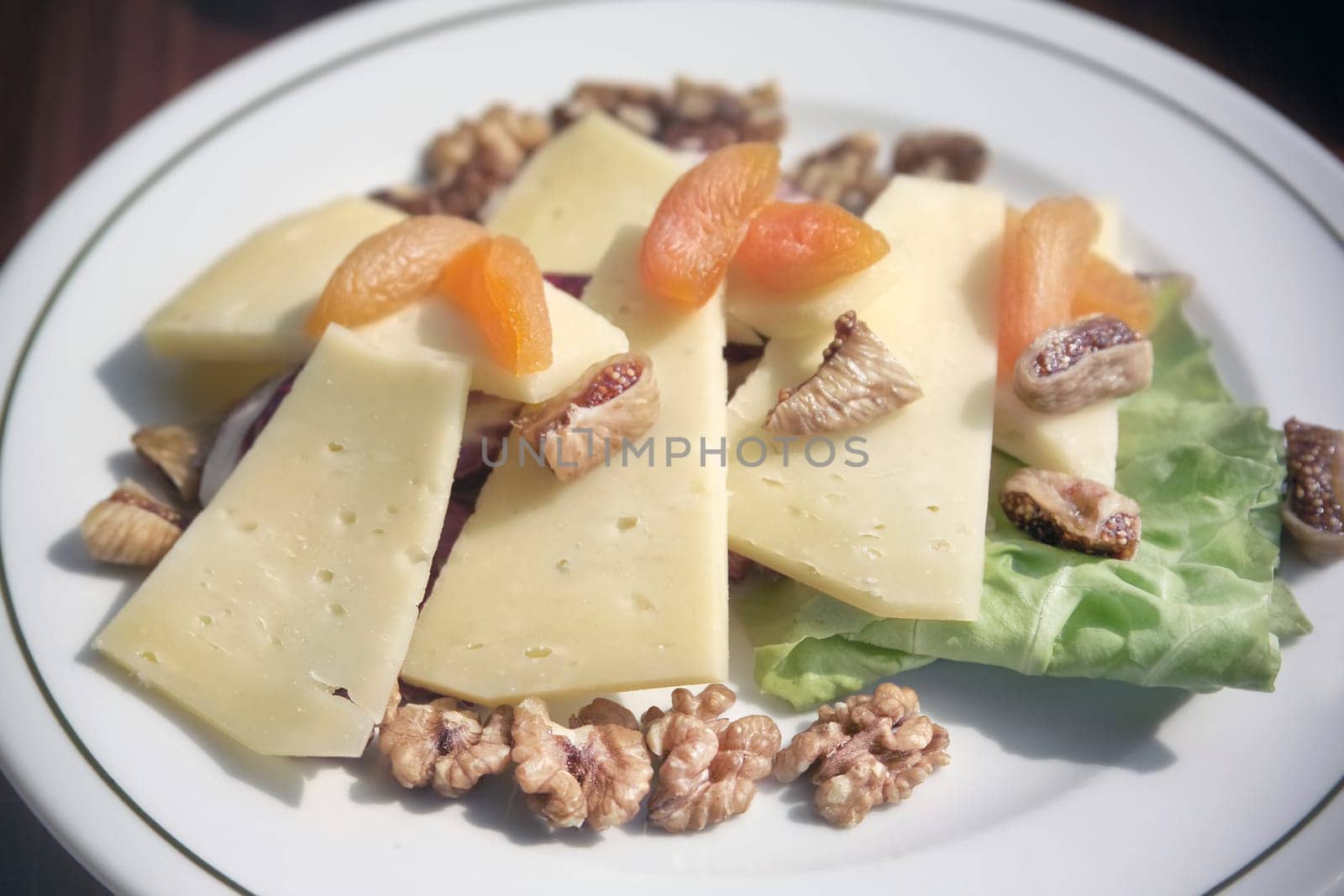 close up plate of cheese and dried fruits with walnut on breakfast table