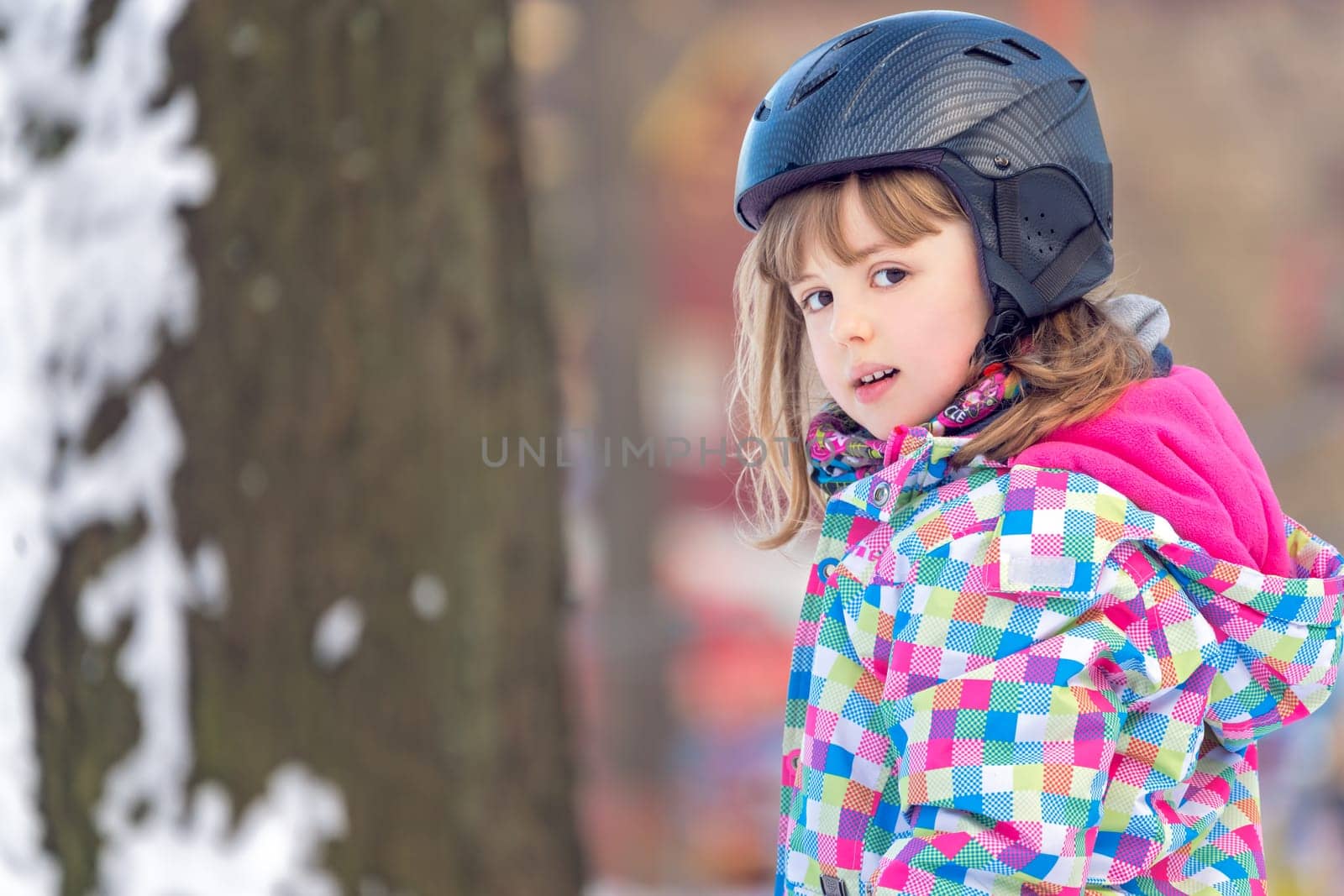 Winter portrait of a little girl wearing ski helmet during skiing lesson
