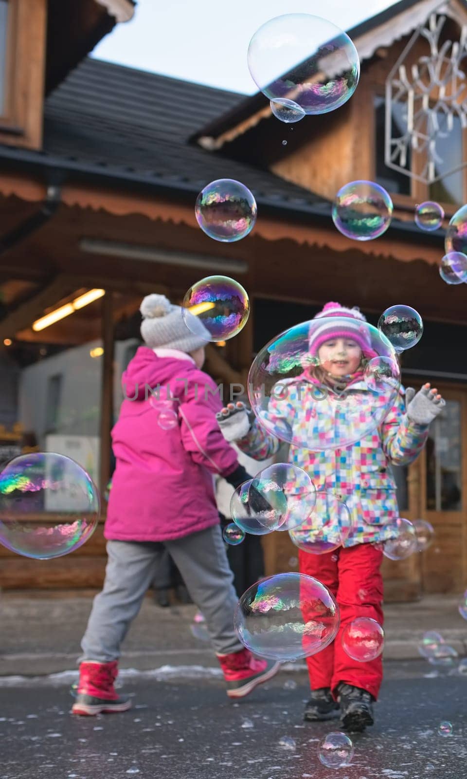 Children trying to catch giant soap bubbles on the main high street in Karpacz town, polish winter ski resort, Poland