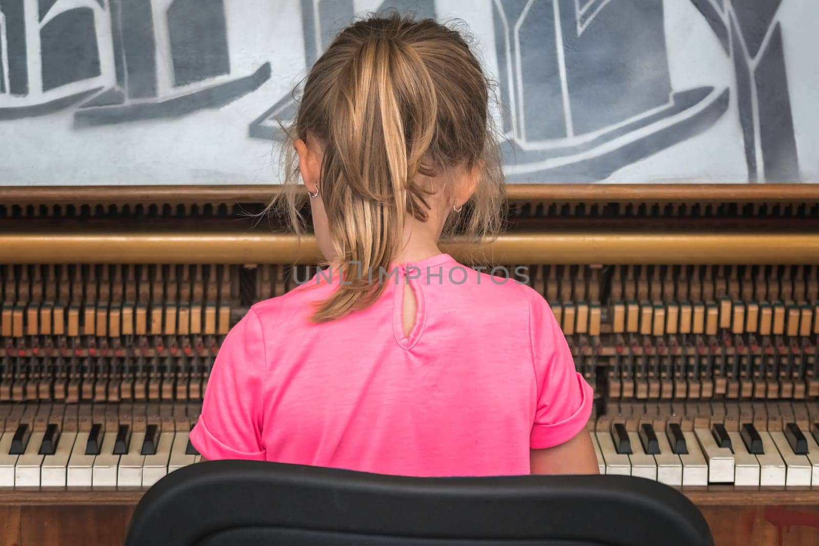 Little young caucasian girl playing on the piano outside train station