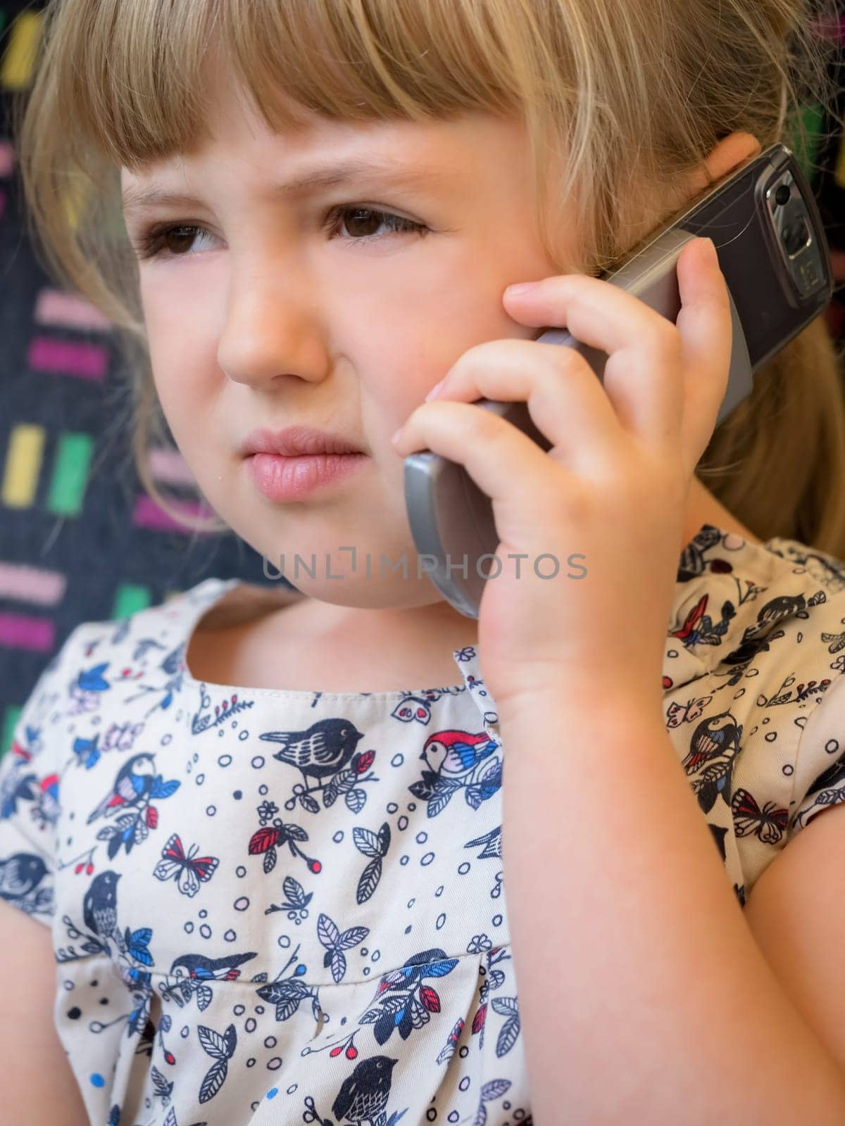 Cute little Caucasian girl talking on the mobile phone while sitting in the train carriage