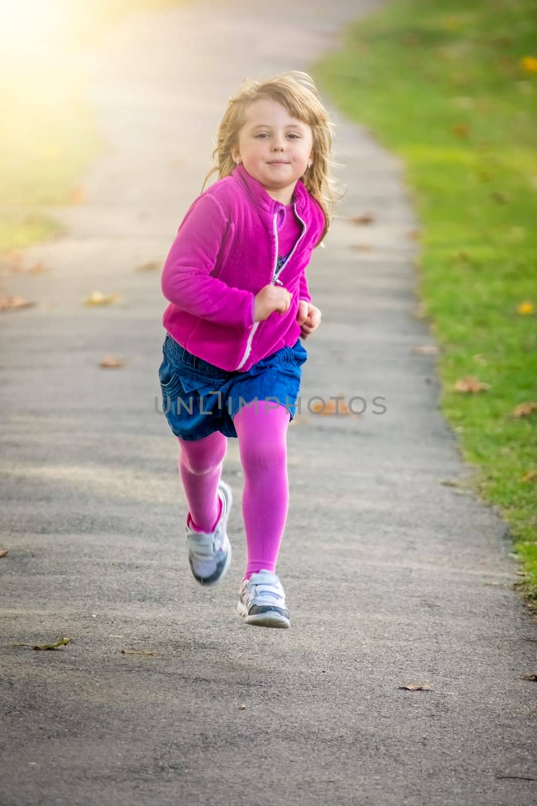 Little Caucasian girl running fast in the park in spring