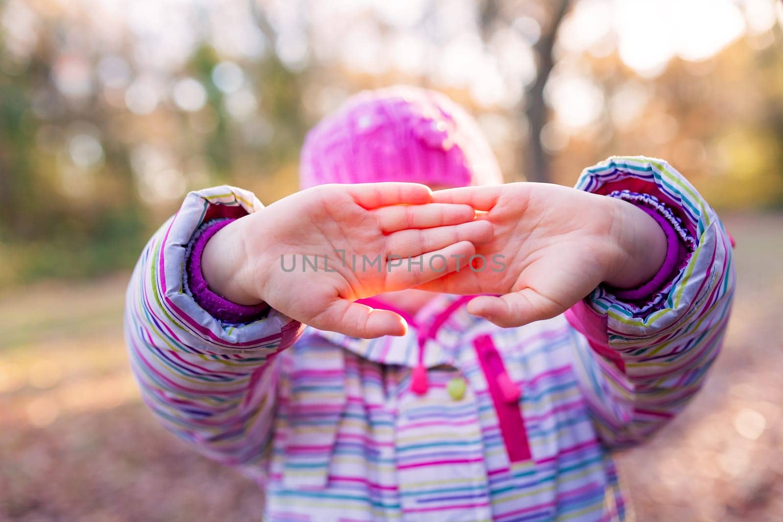 Portrait of young caucasian girl holding her in front of her face in a gesture suggesting to leave her alone