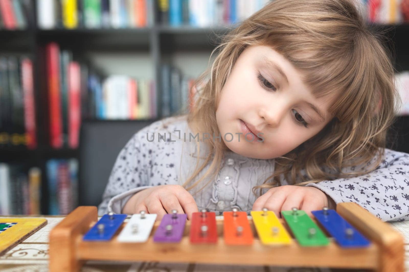 Cute little Caucasian girl playing little colorful cymbals at home