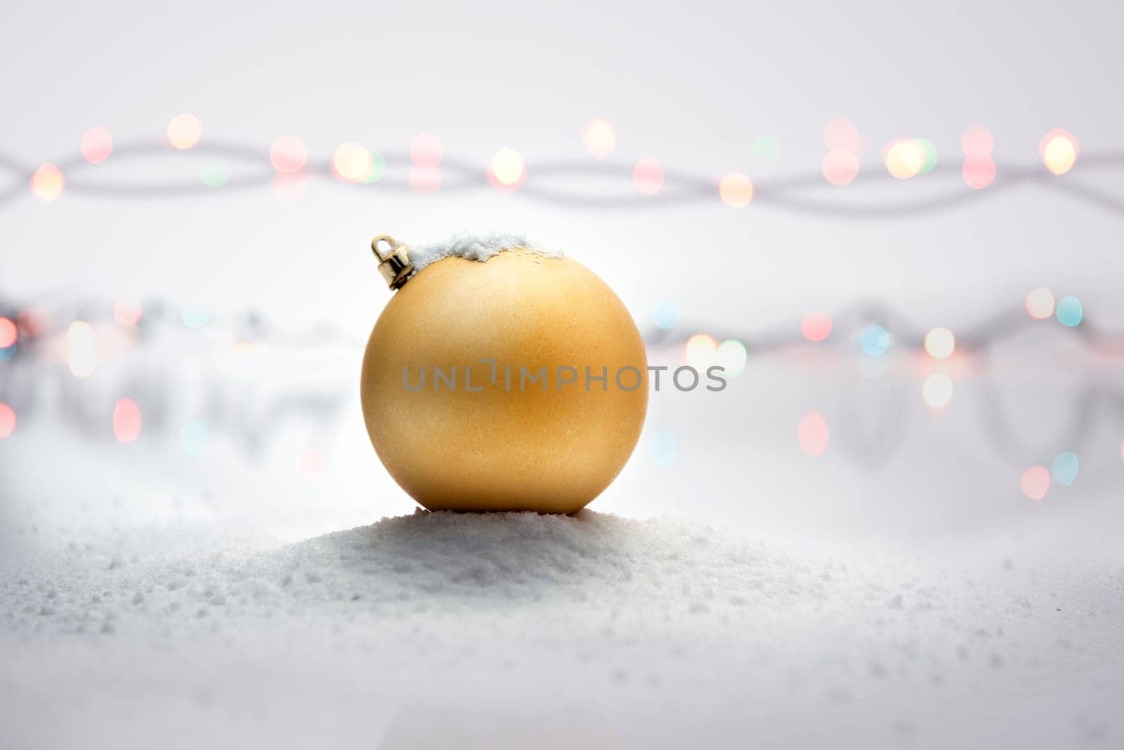 Yellow christmas ball on snow with blurred lights background. Christmas decoration