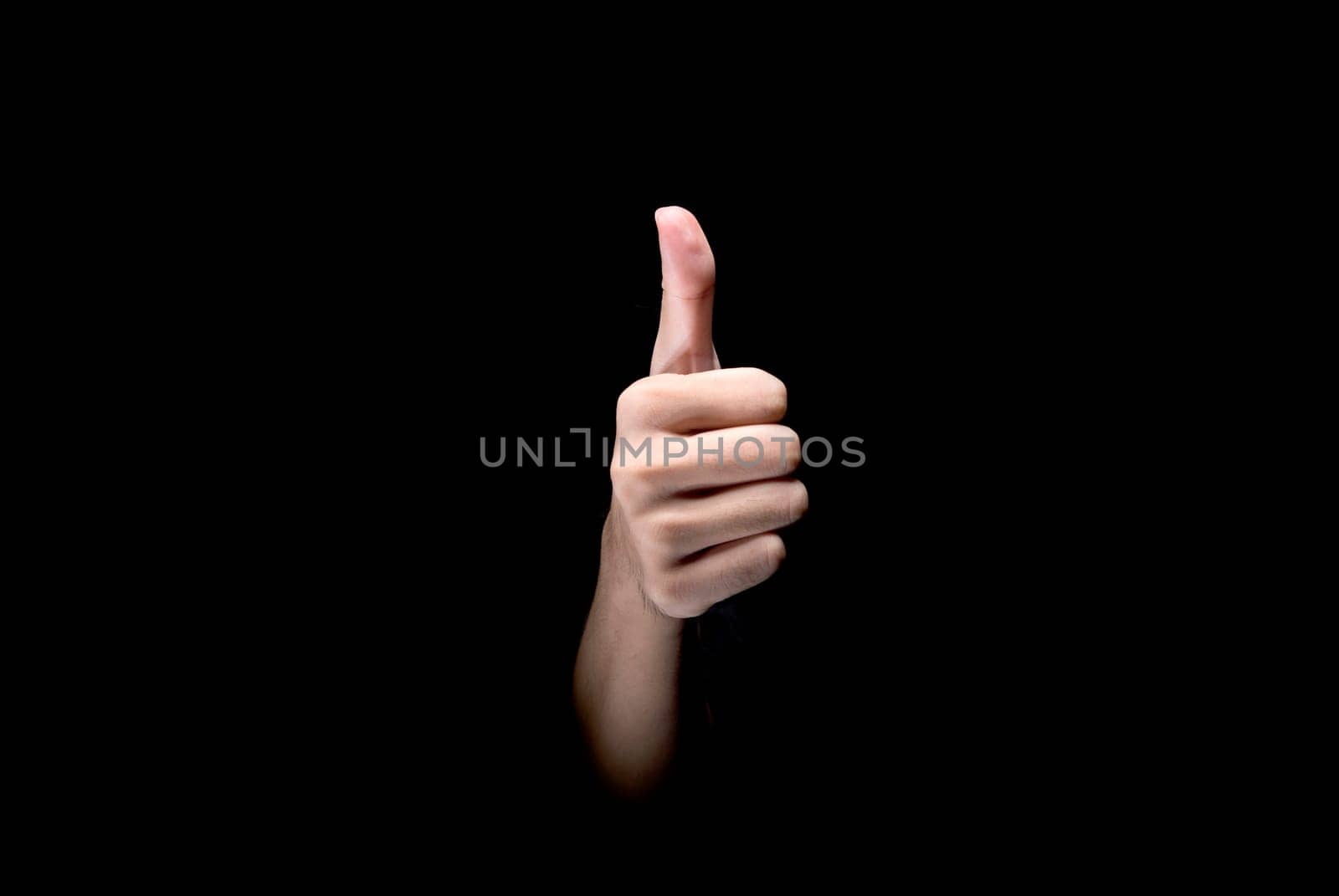 Male hands showing thumbs up gesture over dark background