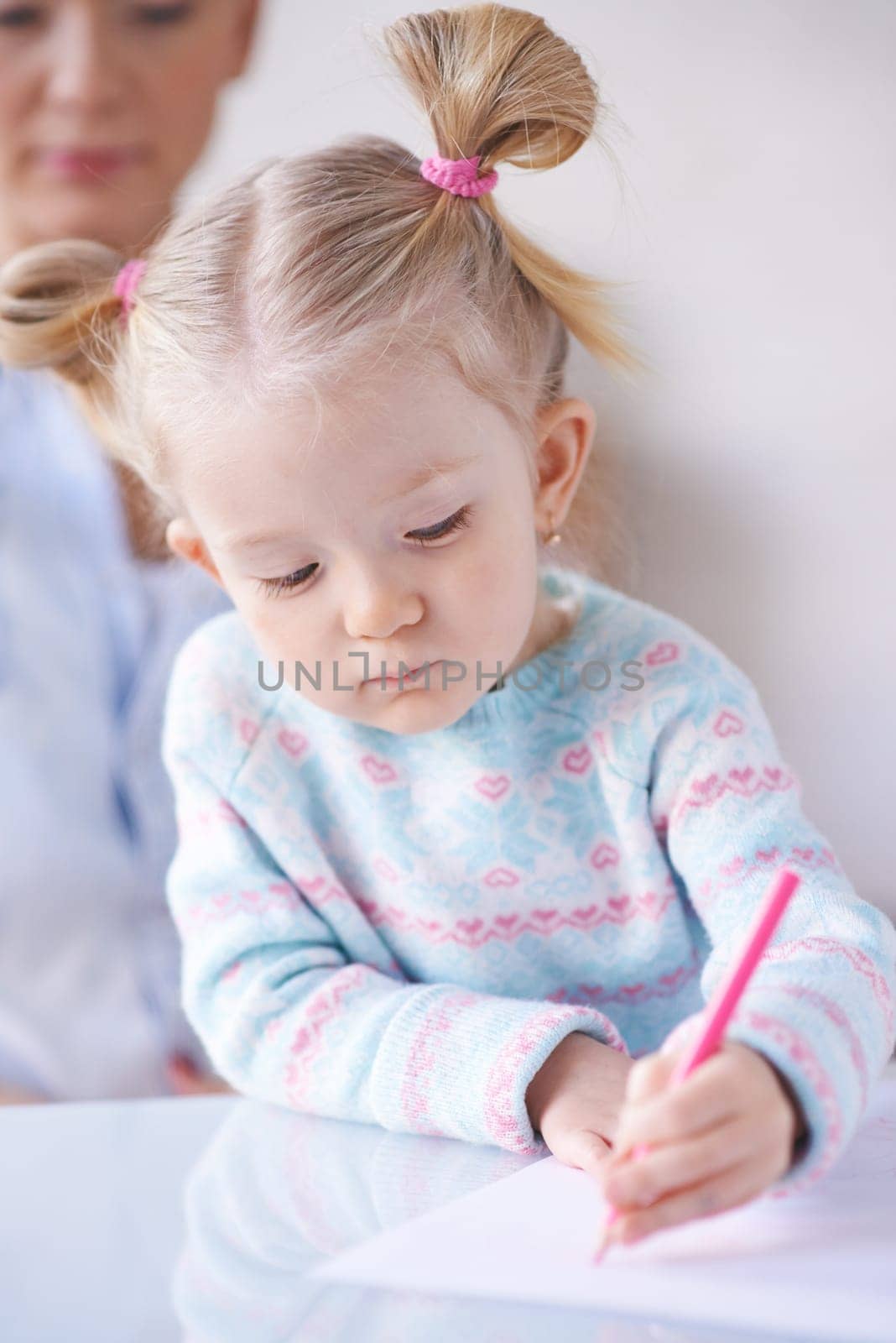 Little girl in casualwear drawing with crayon