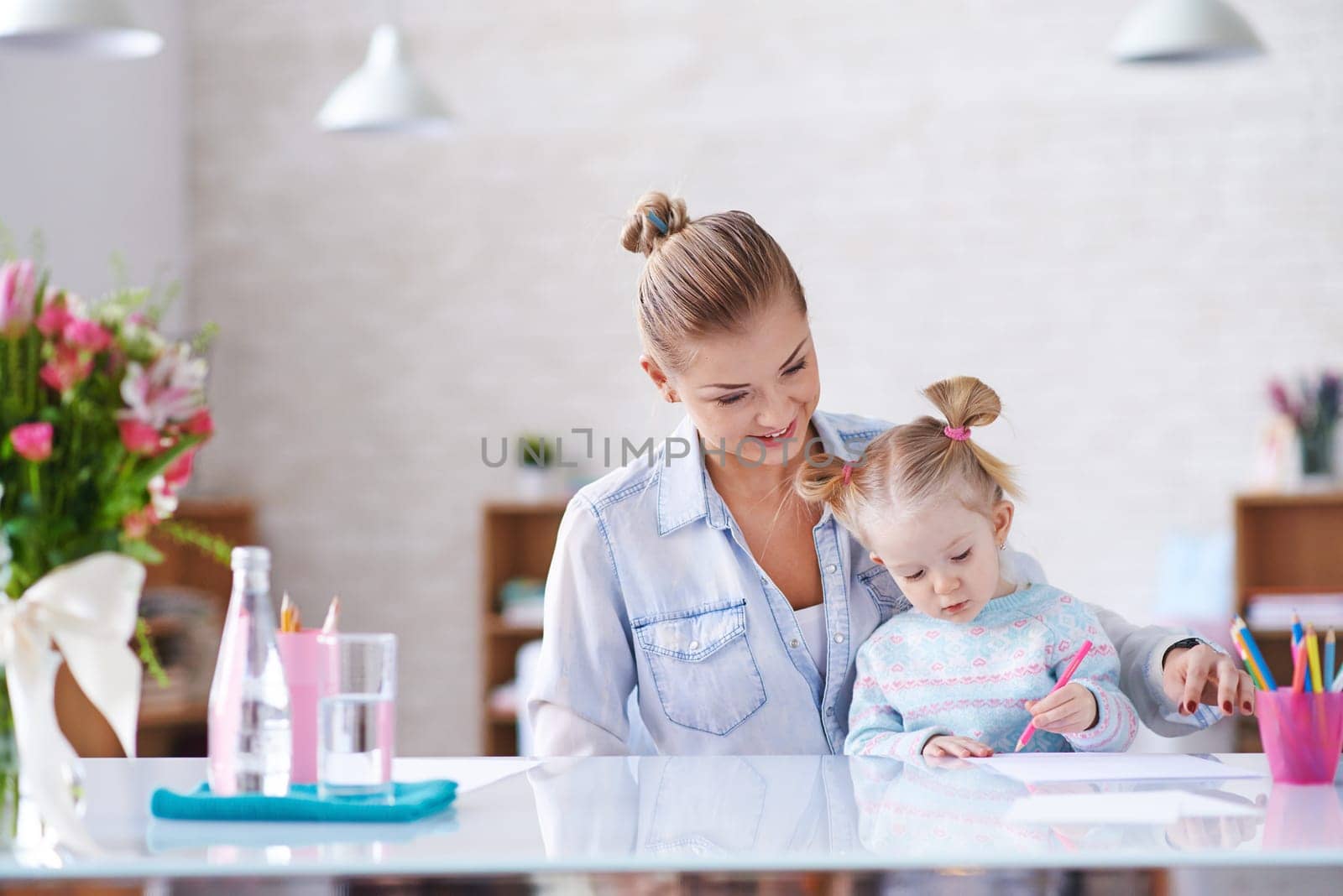 Young mother and her little daughter drawing with crayons