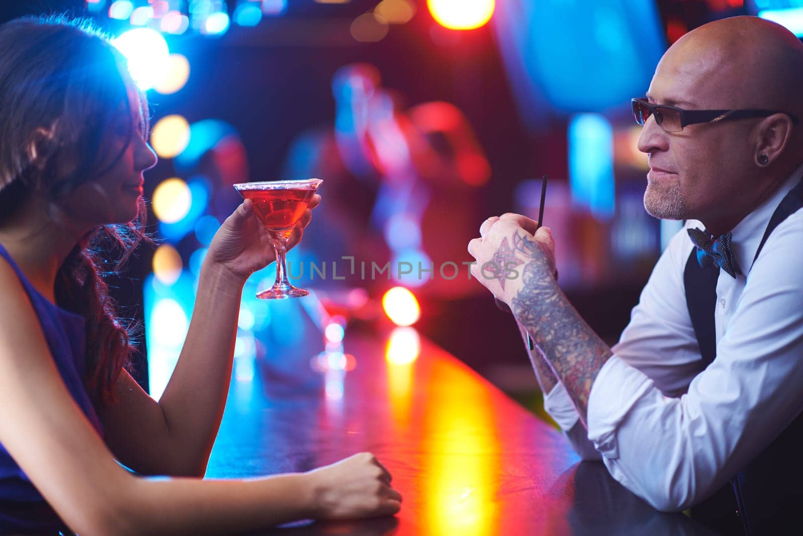 Mature barman and young girl with drink talking in the bar