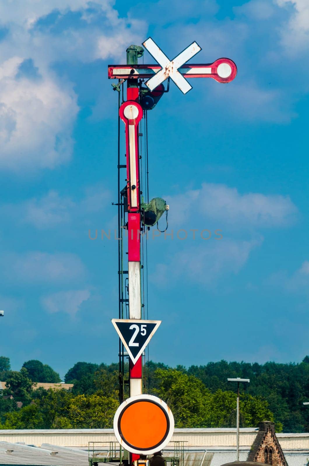 Red White railway signal in front of a blue sky.