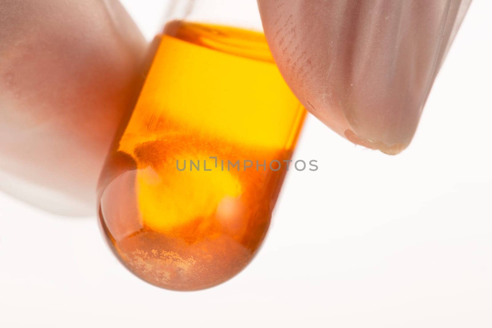 Glowing orange liquid in test tube close up, held by fingers.