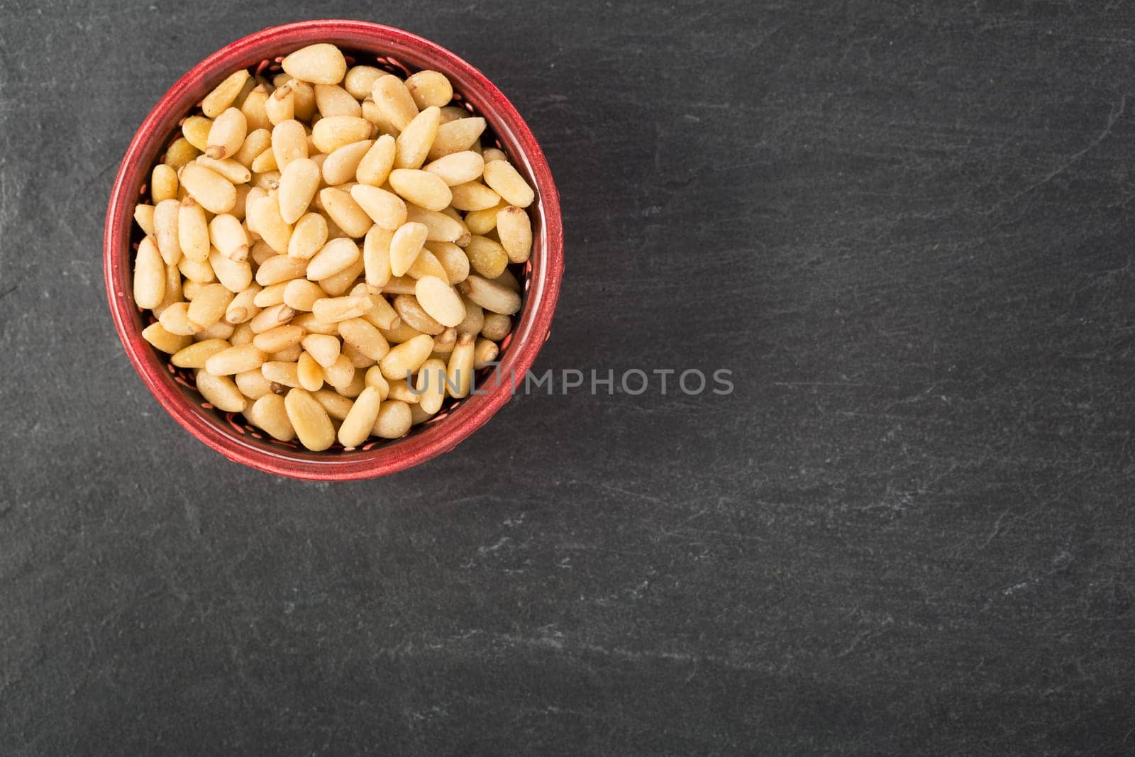 Bowl of pine nuts on a slate surface, view from above with copy space.