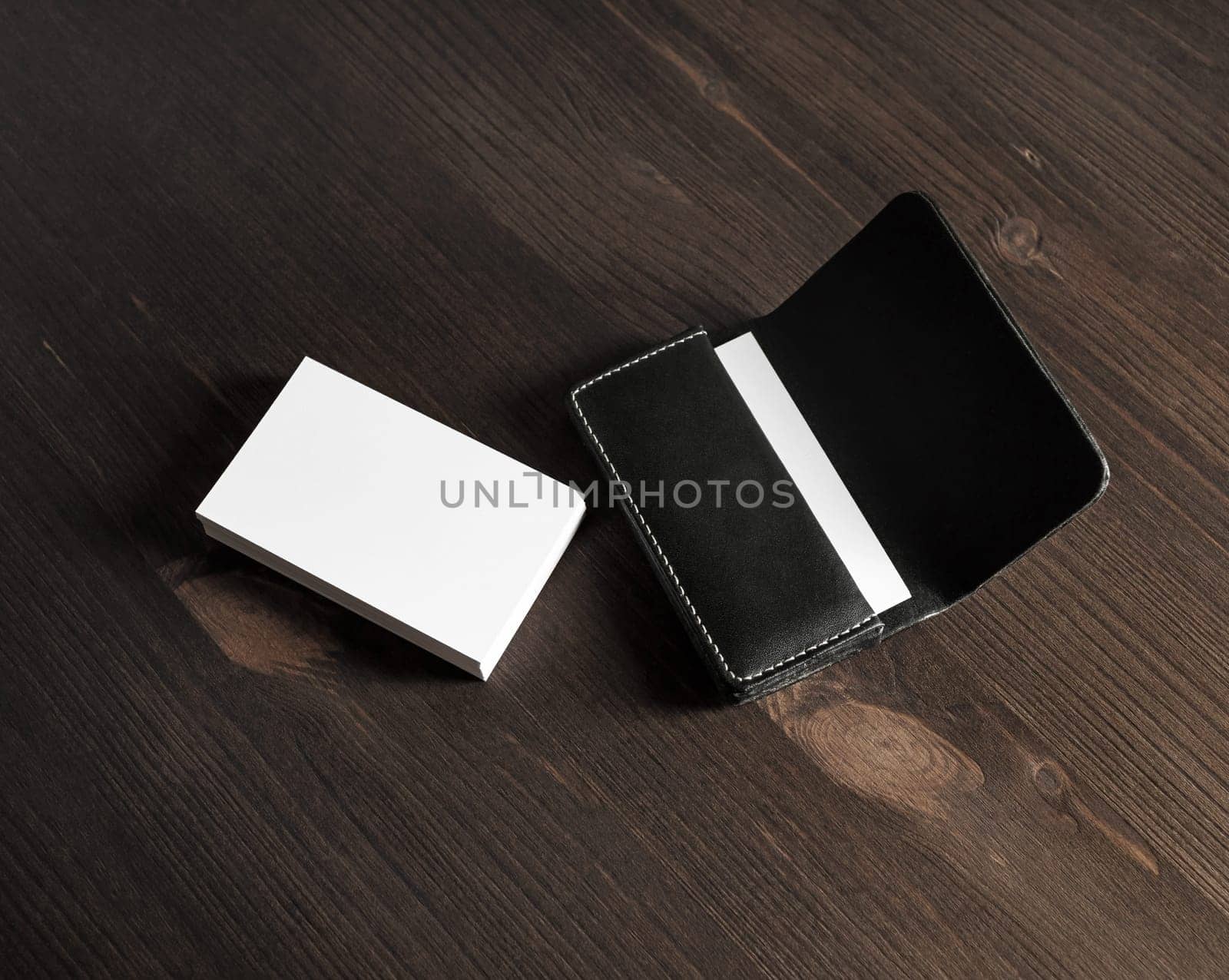 Blank business cards and leather business card holder on wooden background.