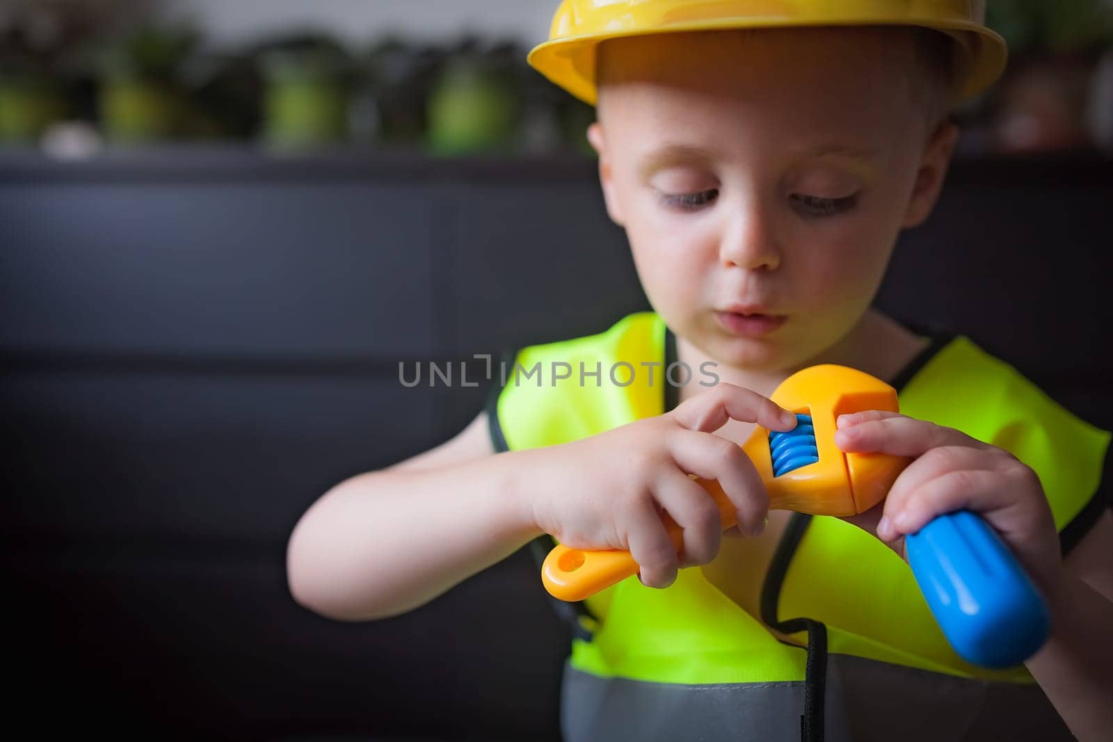 Little cute boy holding plastic toy tools pretending to be a builder foreman