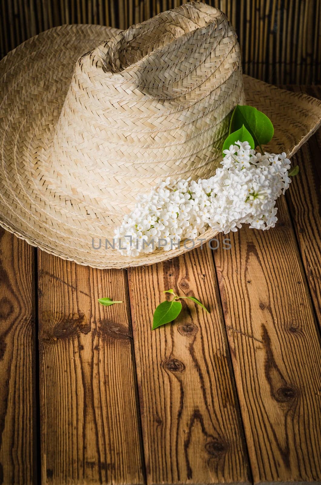 Still-life with a bouquet of lilacs and a straw hat, close-up