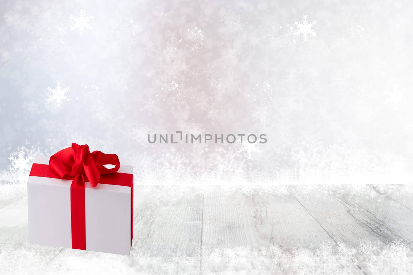 Christmas or Happy New Year decoration background. Christmas gift box on bright table top and snowflakes over abstract festive white winter background. Template for your product display montage. Card concept.