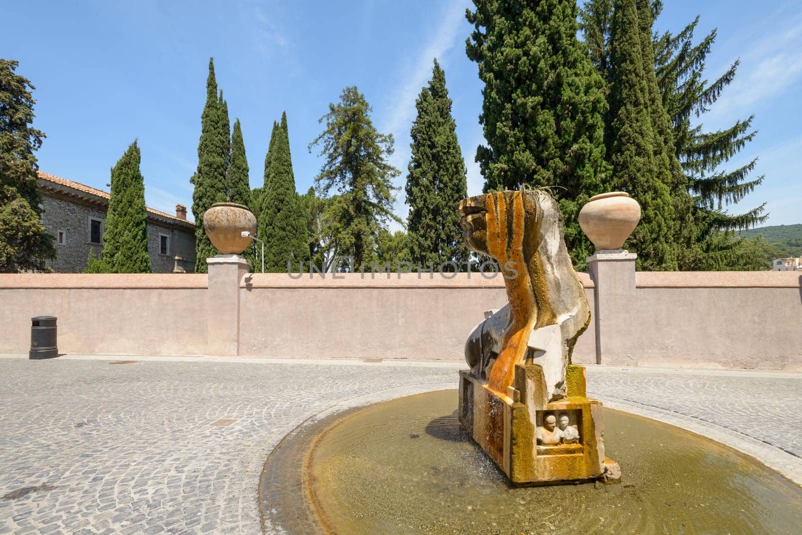 A fountain depicting a head, in a public square in Tivoli, Italy