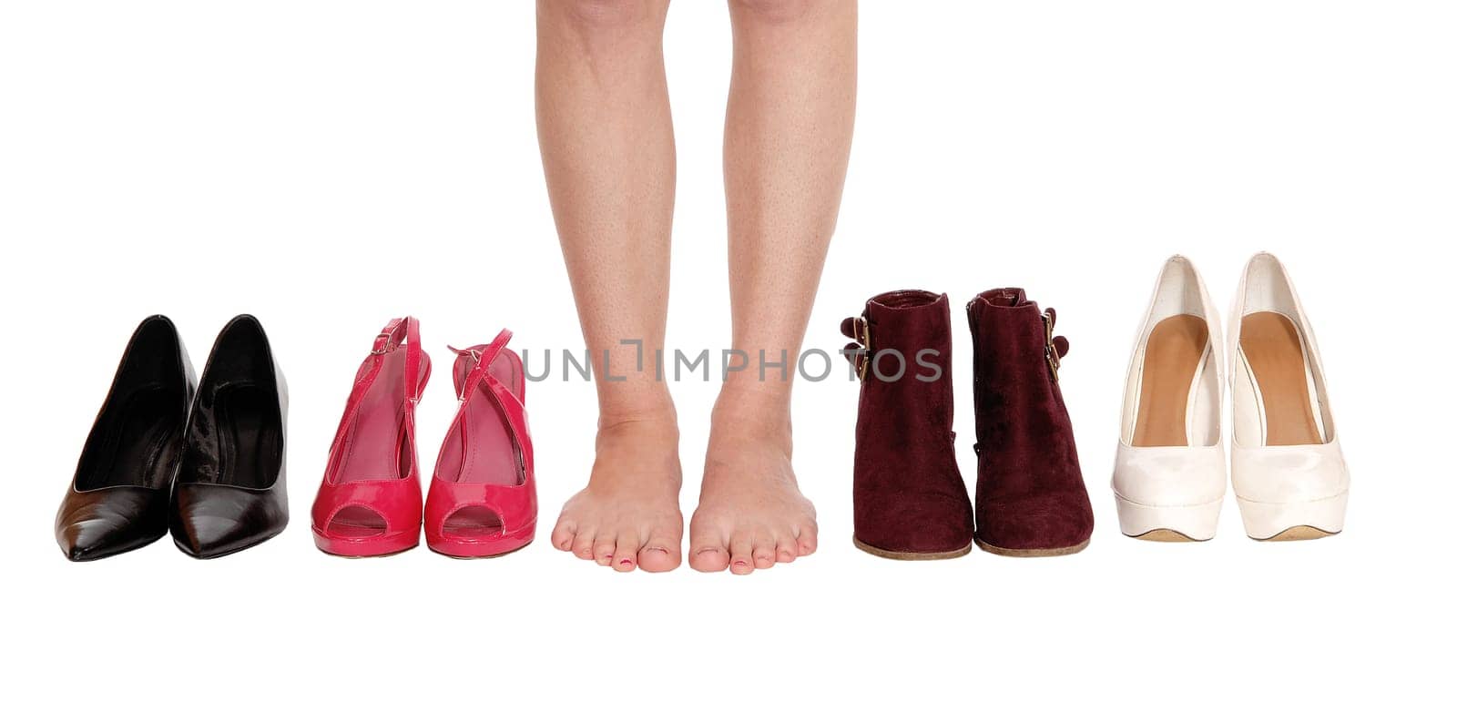 A close up image of a young woman legs standing between four pair.of shoe and high heels, isolated for white background.