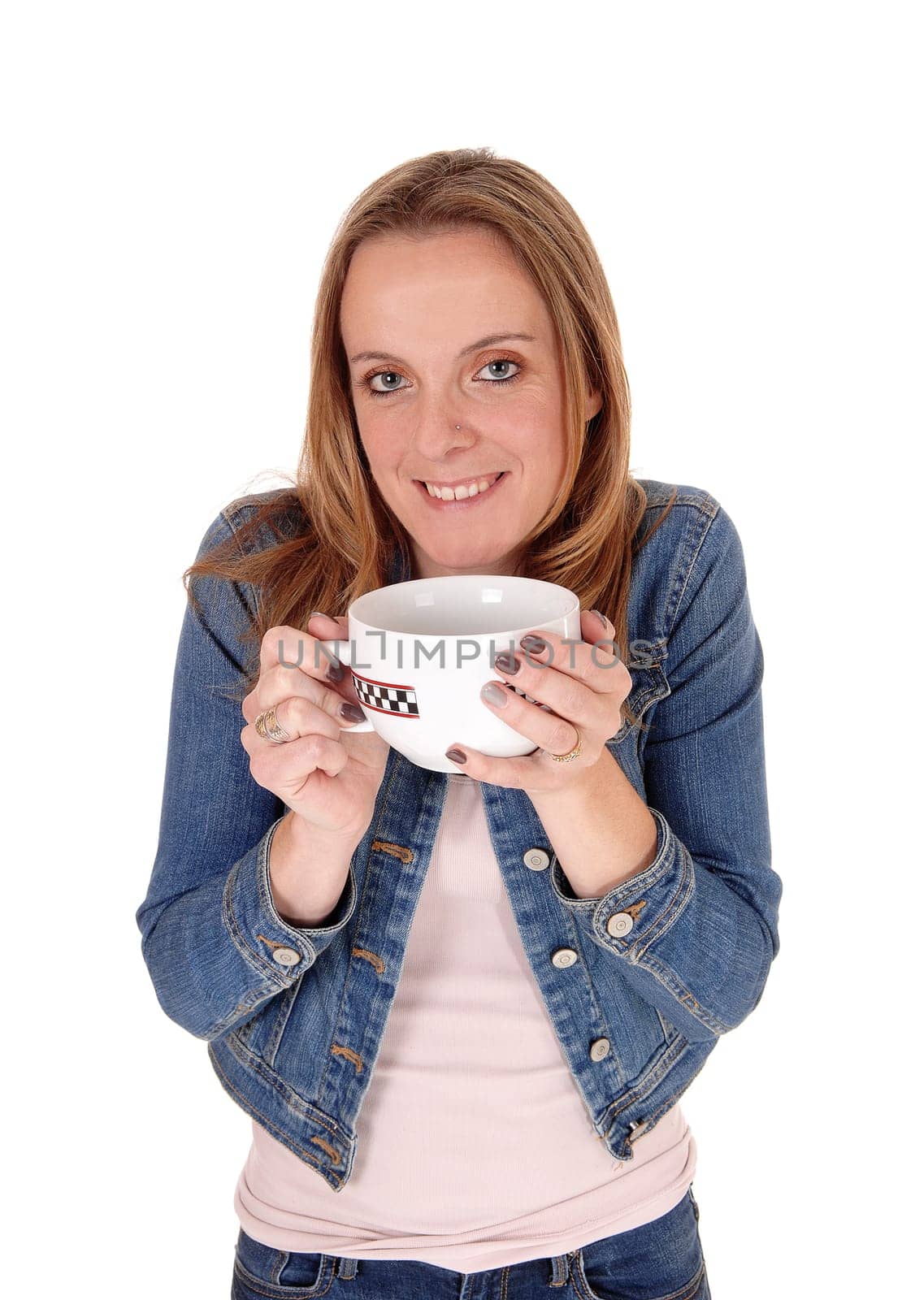 A young woman in a jeans jacket standing and holding a big mug of hot.sup on a cold winter day, isolated for white background.