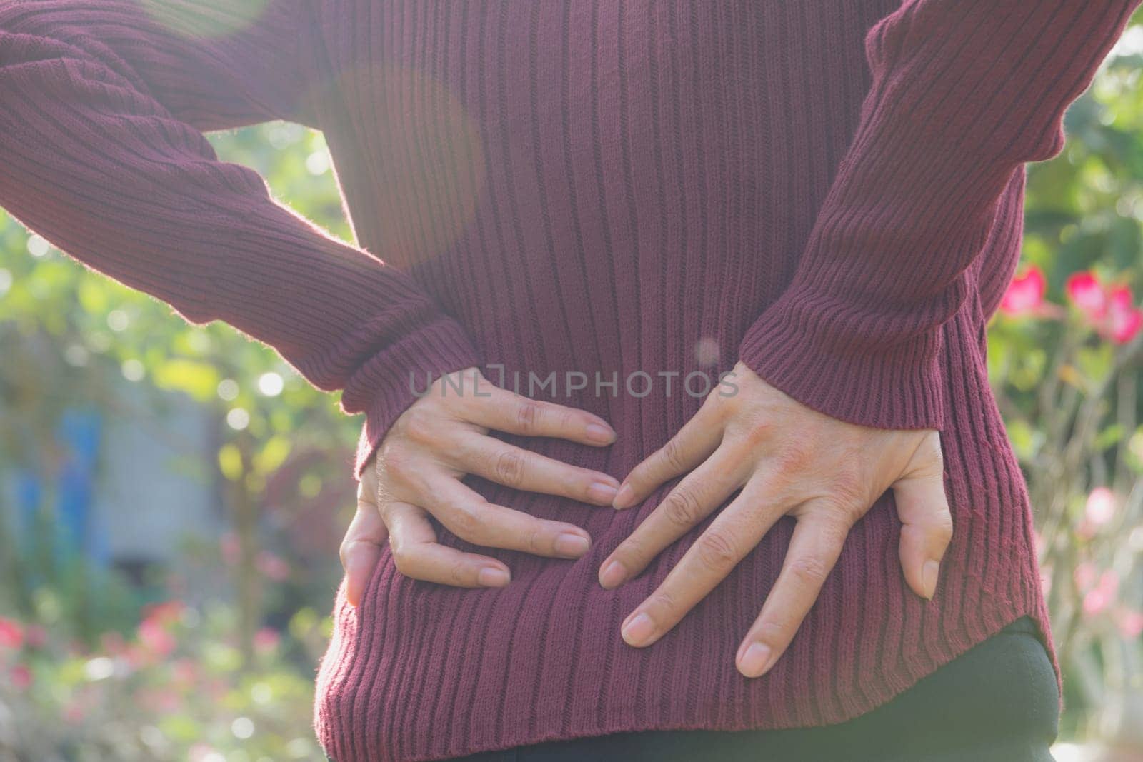 A woman suffering from backache, spinal injury and muscle issue problem at outdoor.