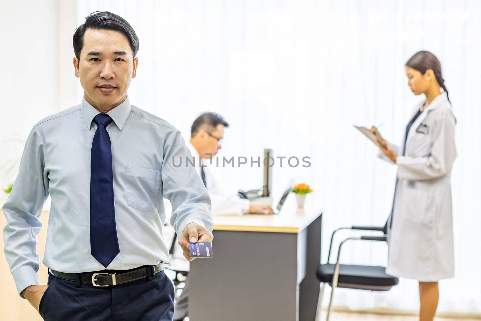 Portrait of Young adult Patient with credit card with examination room medical office background for insurance concept