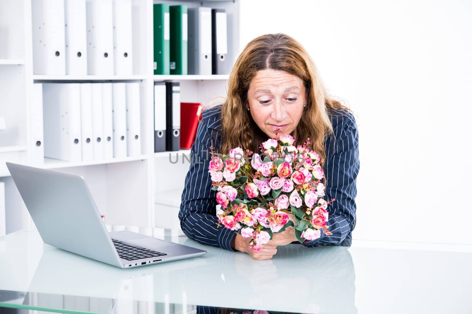 brown-haired  businesswoman in the office with big bouquet of flowers