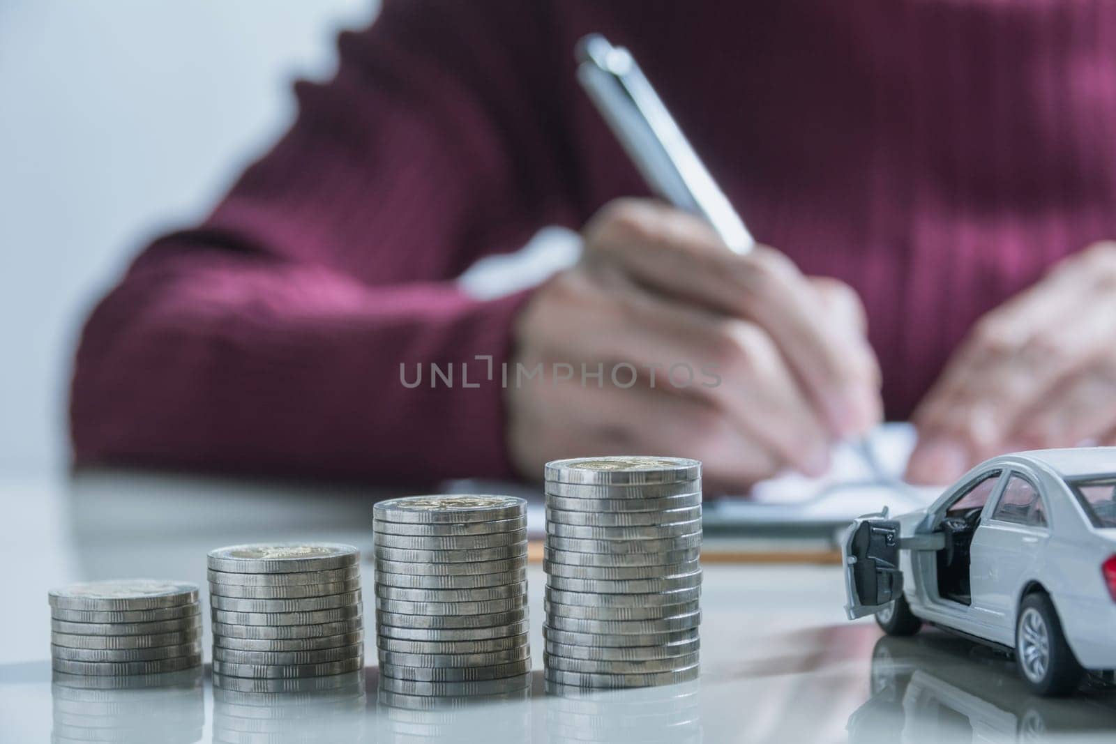 Car insurance and car service. Businesswoman with stack of coins and toy car, business and financial concept.