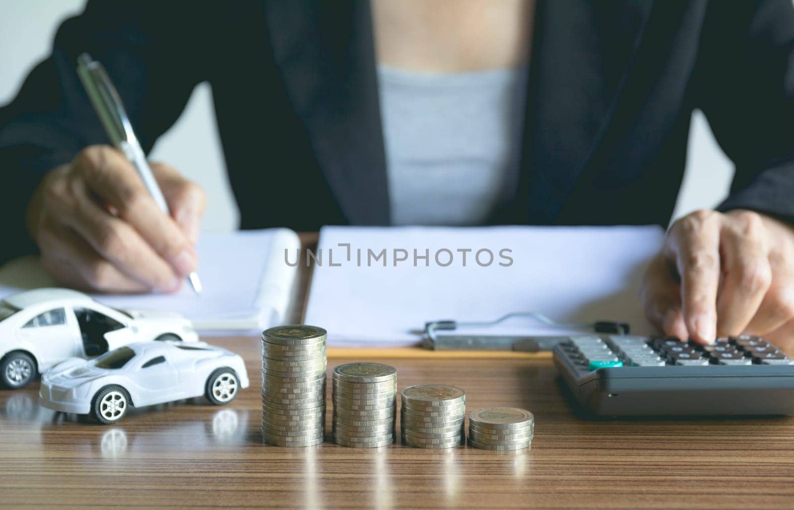 Car insurance and car service. Businesswoman with stack of coins and toy car, business and financial concept.