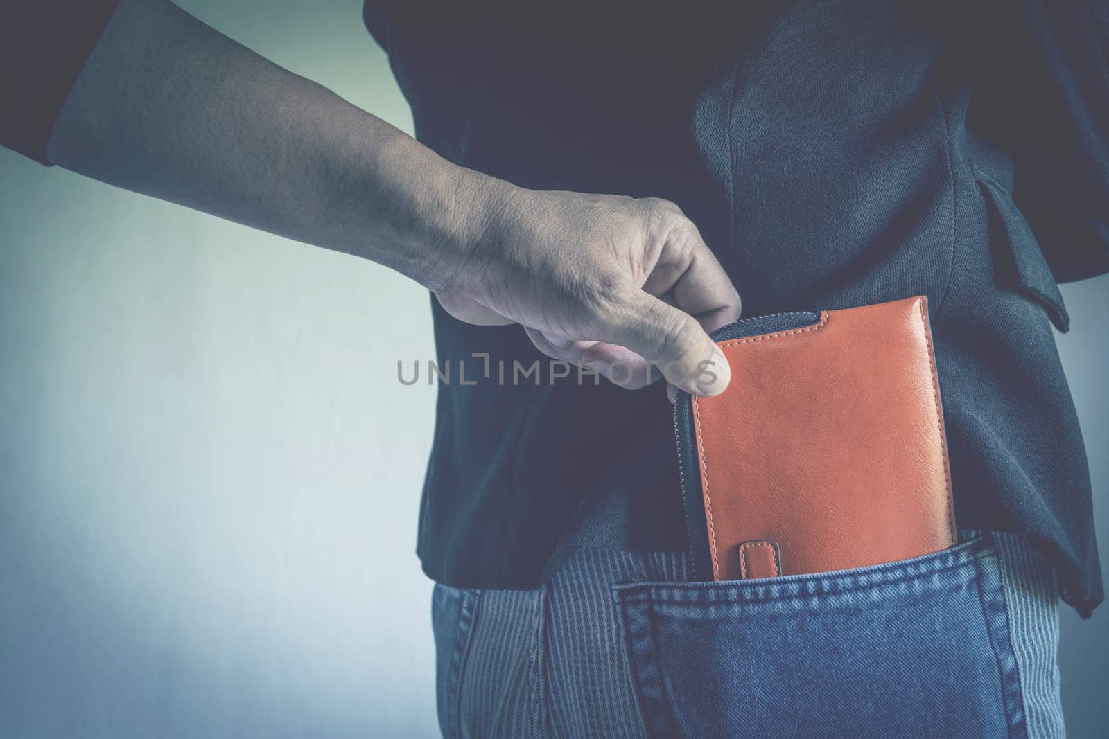Close-up of a the hand of thief stealing the wallet to a woman. Thief stealing wallet from back pocket of a woman.