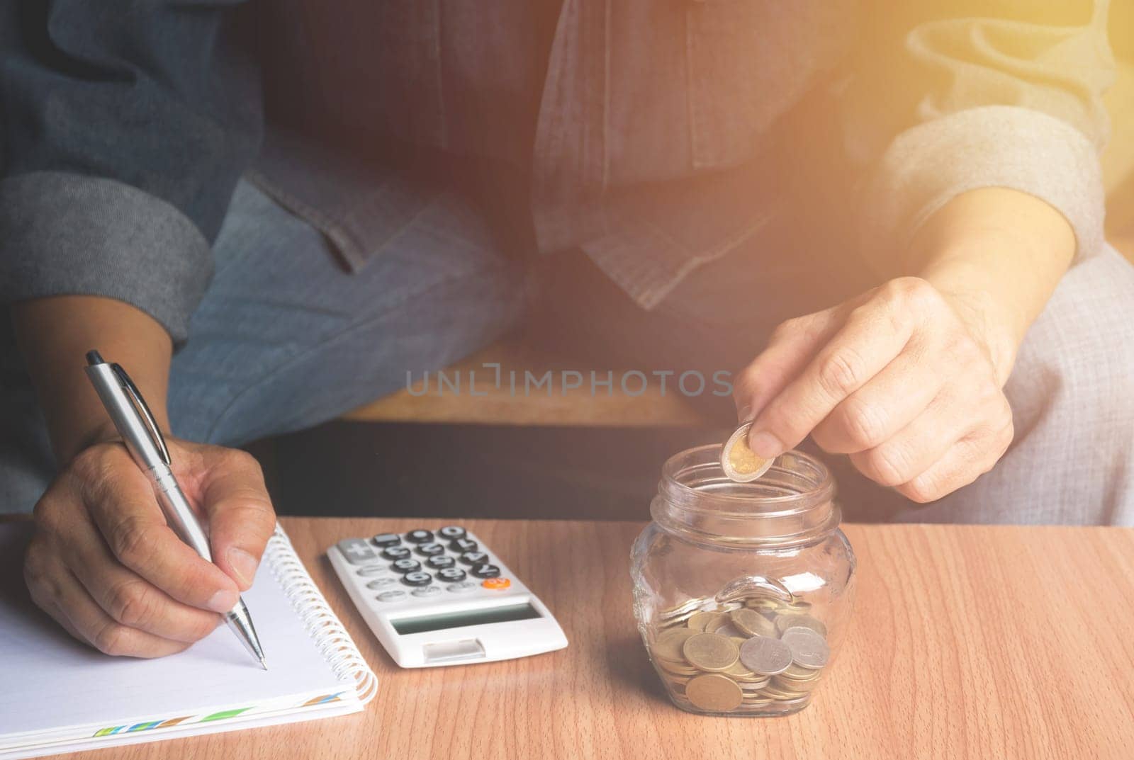 Saving money concept and hand putting money coin in the glass jar for financial and accounting concept.