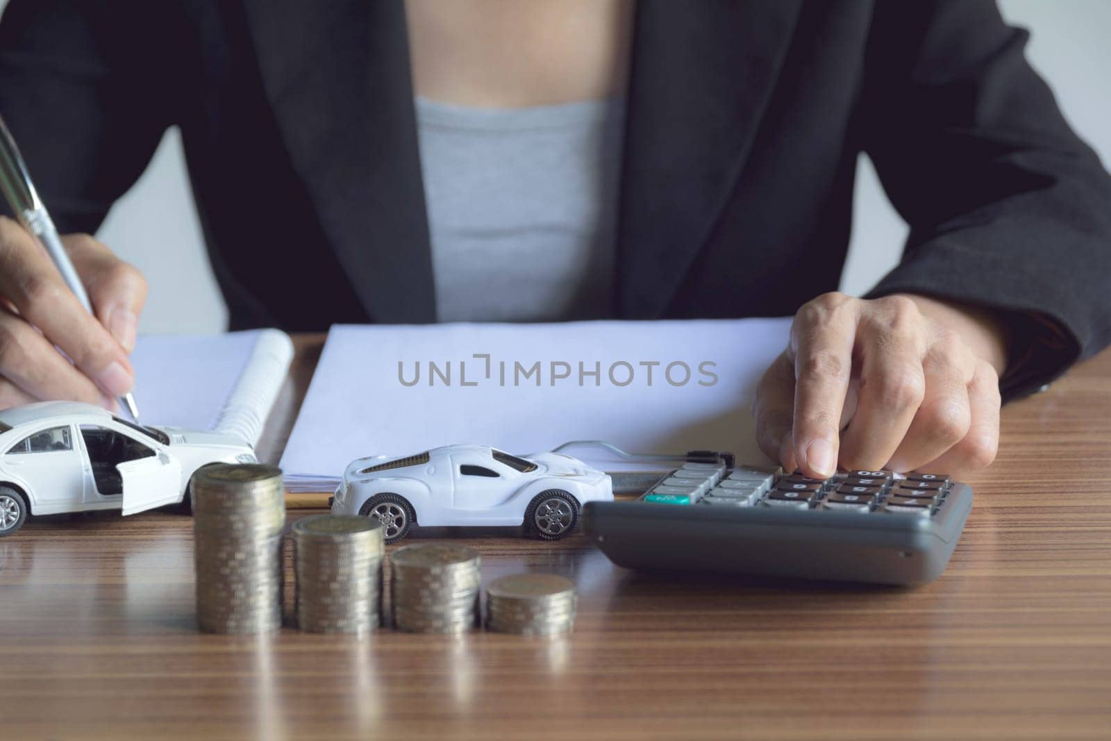 Person working and writing on notebook with stack of coins for financial and accounting concept.