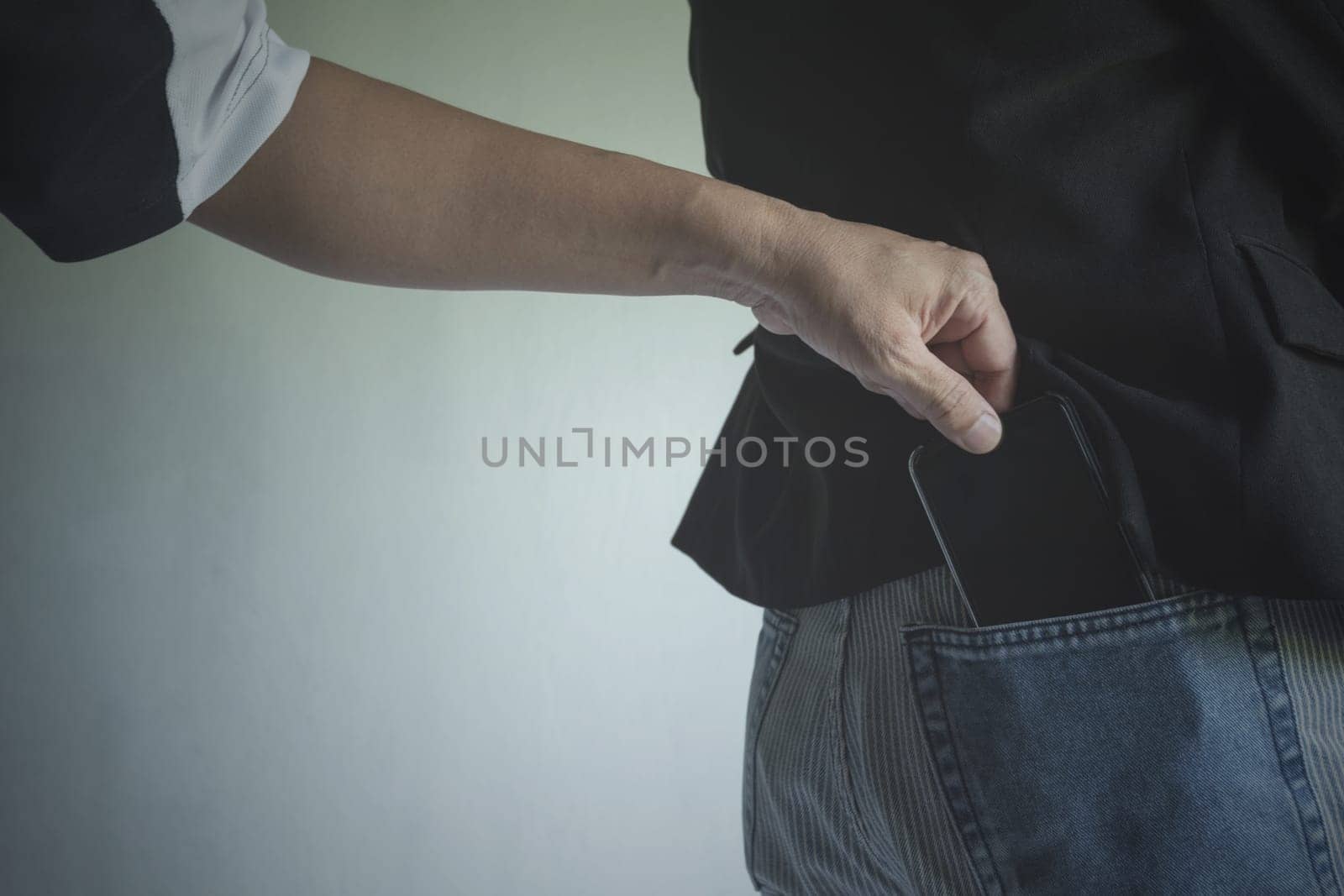 Close-up of a the hand of thief stealing the wallet to a woman. Thief stealing wallet from back pocket of a woman.