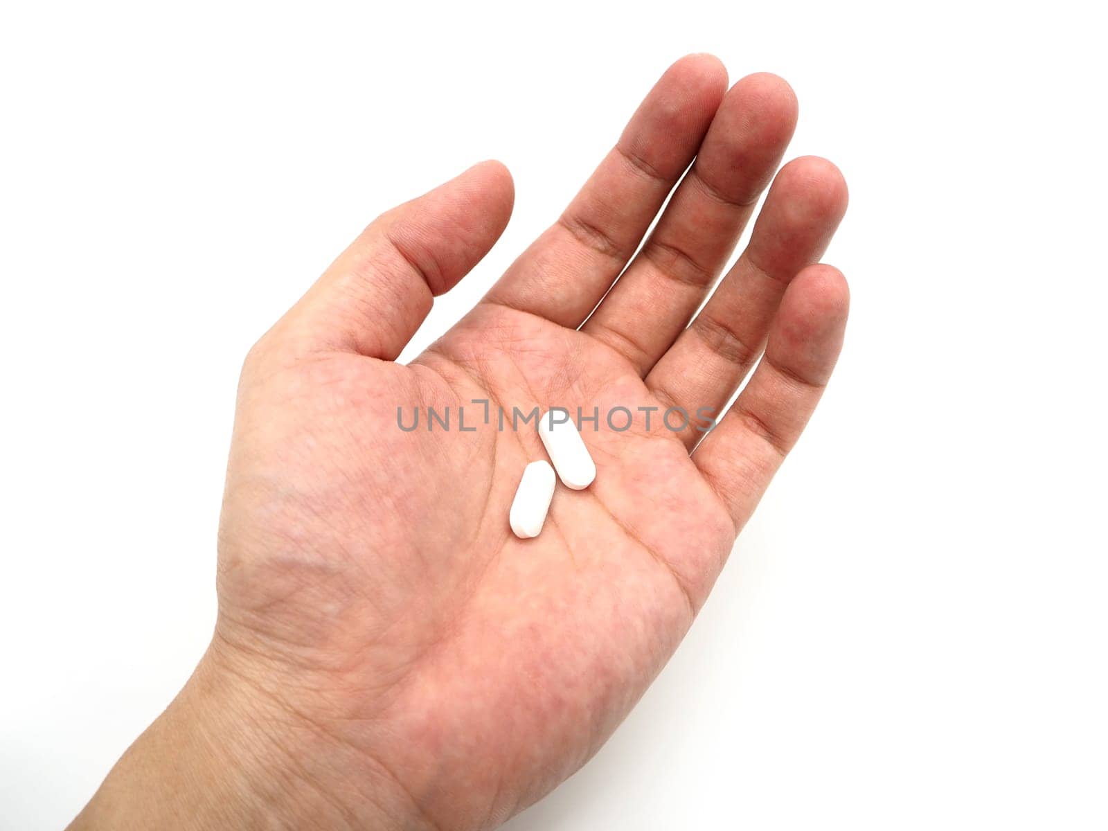 Hand holding a white pills isolated on white background.