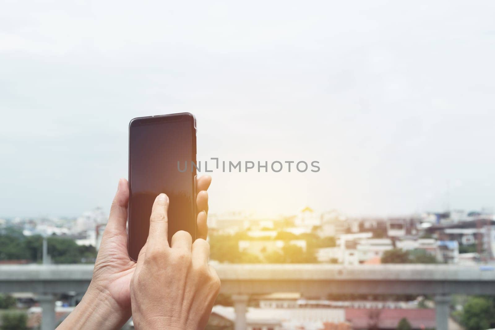 Woman hand holding and using smart phone with buildings background.