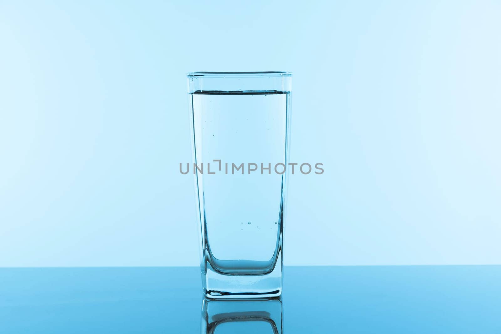 Water glass on blue background. Glass with clean drinking water.
