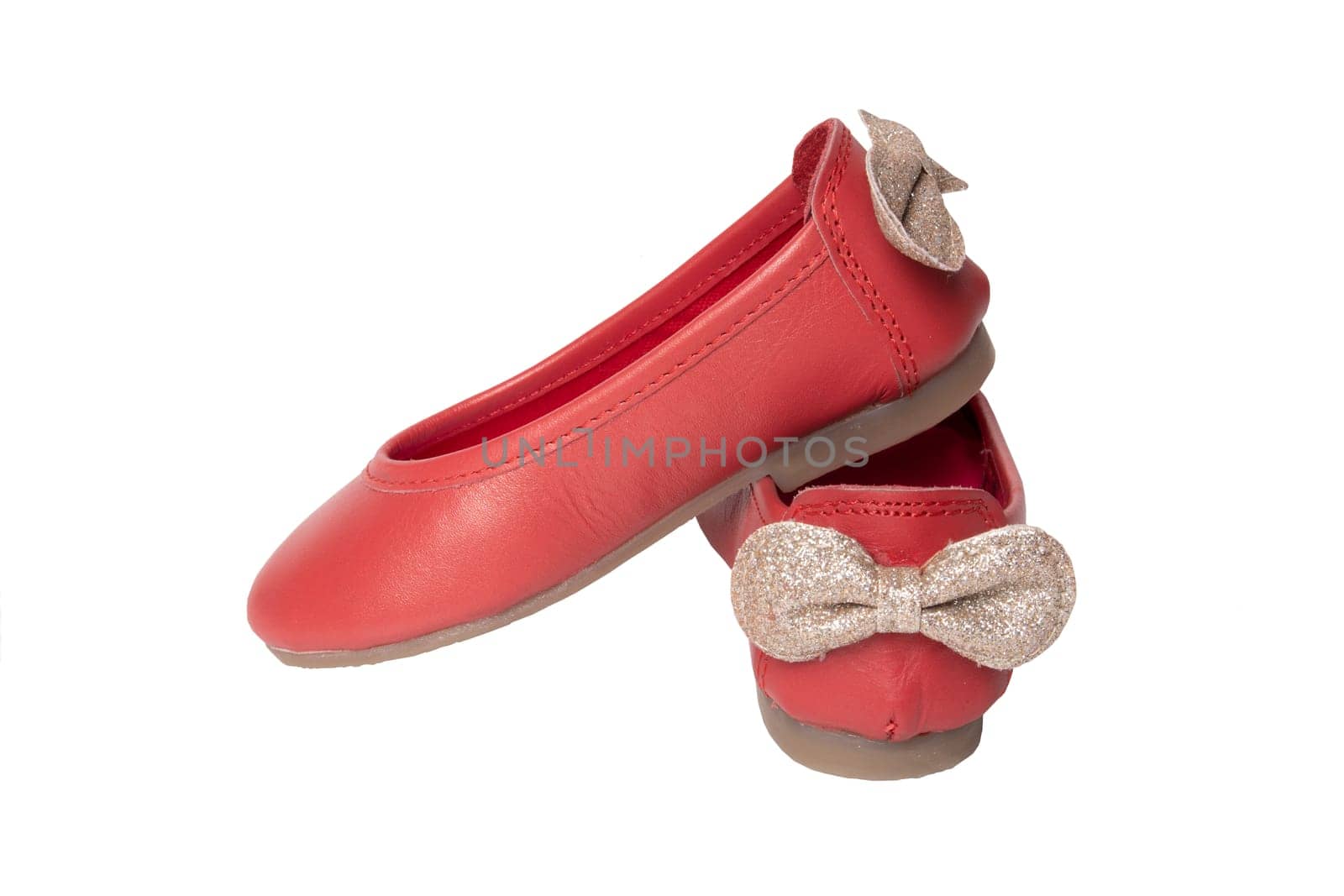 Red shoes. Closeup of red girls shoes with a golden bow isolated on a white background. Fashionable footwear.