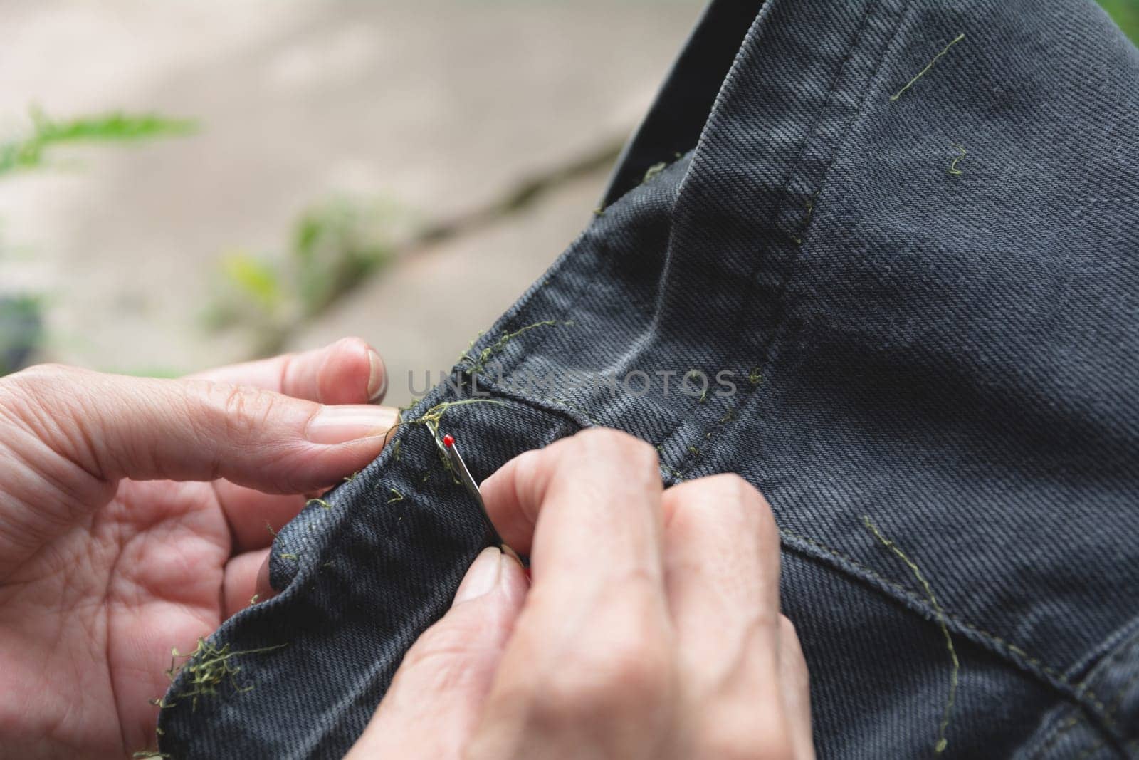 Hand holding and using sewing seam ripper. Ripping a seam with a ripper.