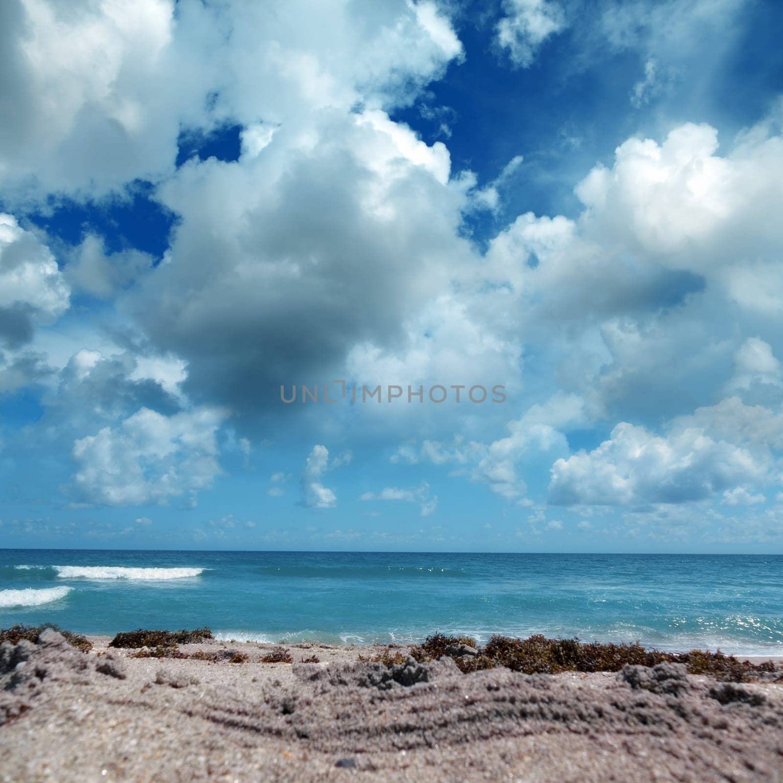 Close up seascape with sandy beach and waves on sea over cloudy sky in Deerfield Beach, Florida, USA