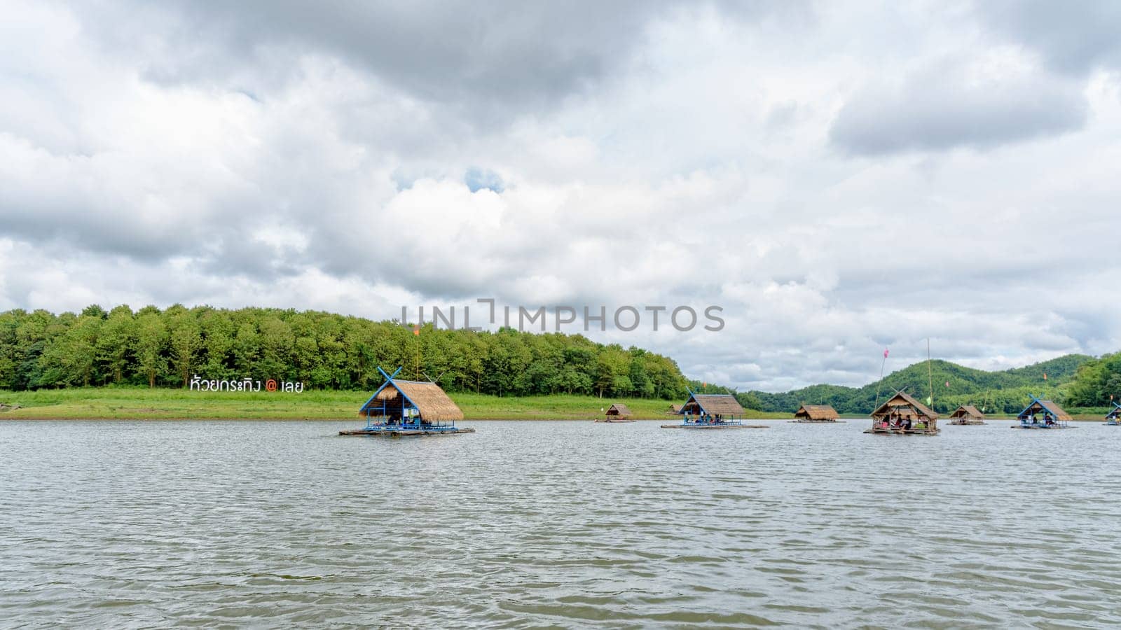 Bamboo raft shelter are floating restaurant in the middle of water under the blue sky as a tourist attraction at Huai Krathing Reservoir, Loei province, Thailand, 16:9 widescreen